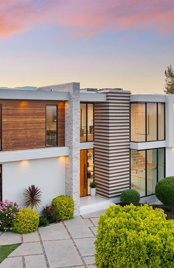 A Contemporary two-level home on hillside with shrubs and trees